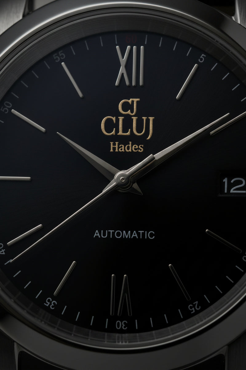Close-up of a Cluj Hades automatic watch dial, featuring a black textured face with silver-tone Roman numerals, stick indices, and hands, a date window at the 3 o'clock position, and a silver-tone stainless steel bezel.