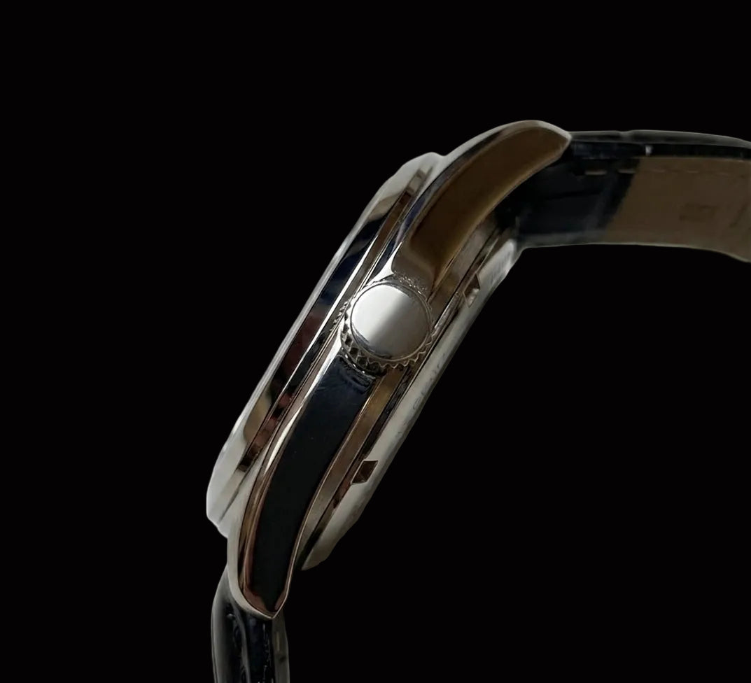 Close-up side view of a wristwatch with a polished silver-tone metal case and a dark blue leather strap on a white background.